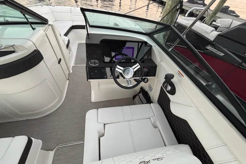 Slide: The Image of 2019 Sea Ray SDX 270 boat interior with steering wheel and seating, docked by the water. - 22