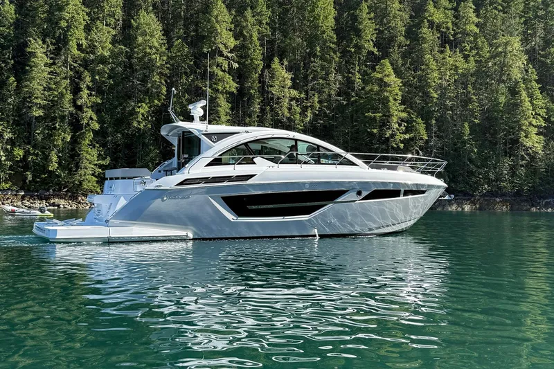 The Image of 2024 Cruisers Yachts 50 Cantius on serene water, surrounded by lush forest. - 0