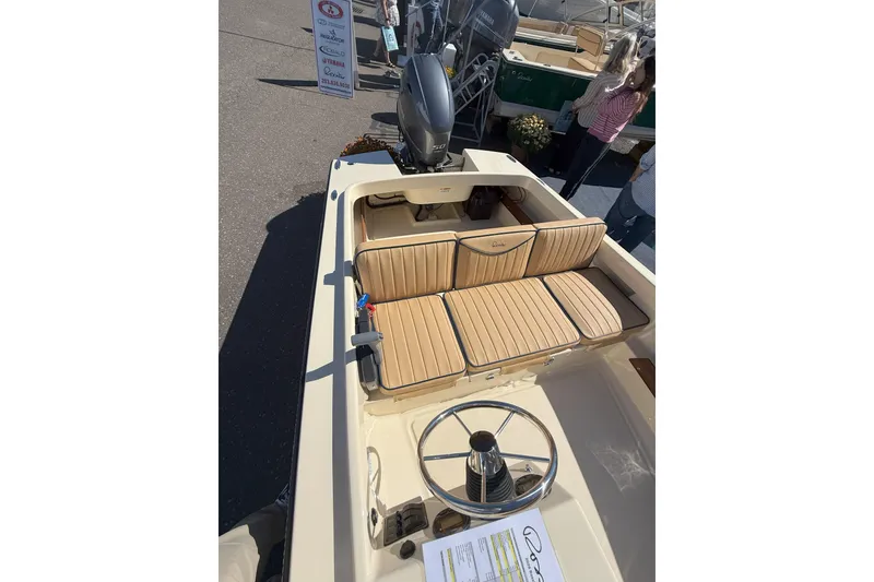 Slide: The Image of 2026 Rossiter 14 Sport boat with tan seating and steering wheel, displayed outdoors. - 5
