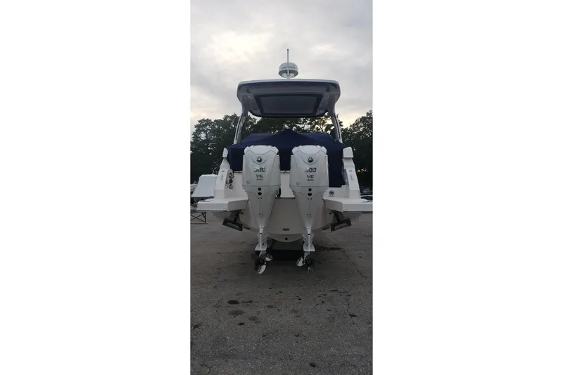 Slide: The Image of 2023 Regal 33 XO boat with dual outboard engines, parked on a concrete surface. - 2