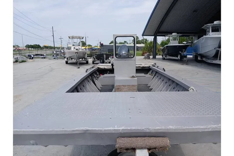 Slide: The Image of Custom 1983 model 18 boat with open deck, parked outdoors near other boats. - 5