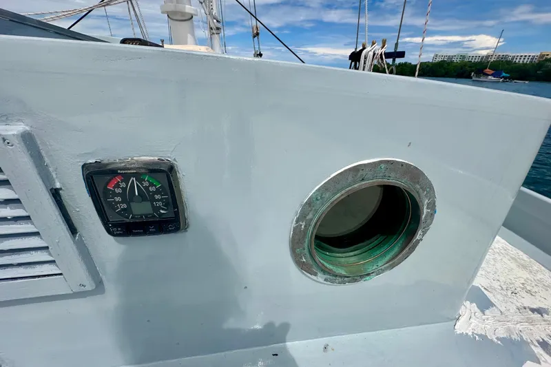 Slide: The Image of Schooner Leopard 1994 boat detail with compass and porthole, clear sky background. - 53