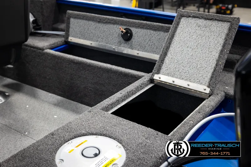 Slide: The Image of 2025 Lund Rebel XL SS boat interior with open storage compartment and Reeder-Trausch Marine branding. - 14