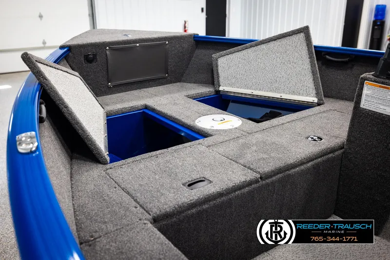 Slide: The Image of 2025 Lund Rebel XL SS boat interior with open storage compartments, gray carpeting, and blue accents. - 16