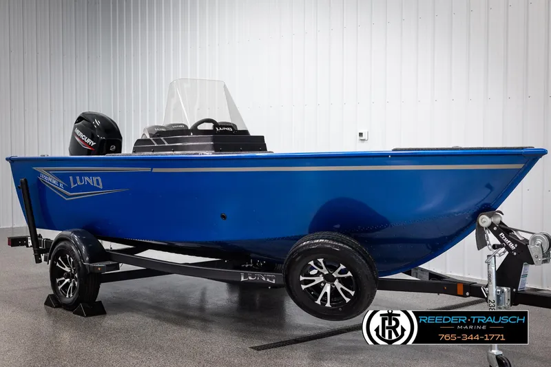 Slide: The Image of 2025 Lund Rebel XL SS boat in blue on trailer, displayed indoors. - 2