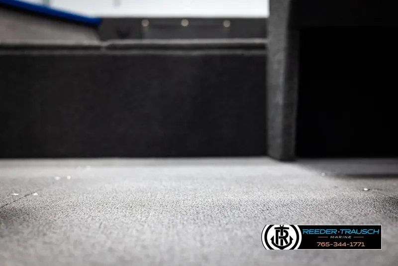 Slide: The Image of 2025 Lund Rebel XL SS boat interior with carpeted flooring, Reeder-Trausch Marine logo visible. - 29