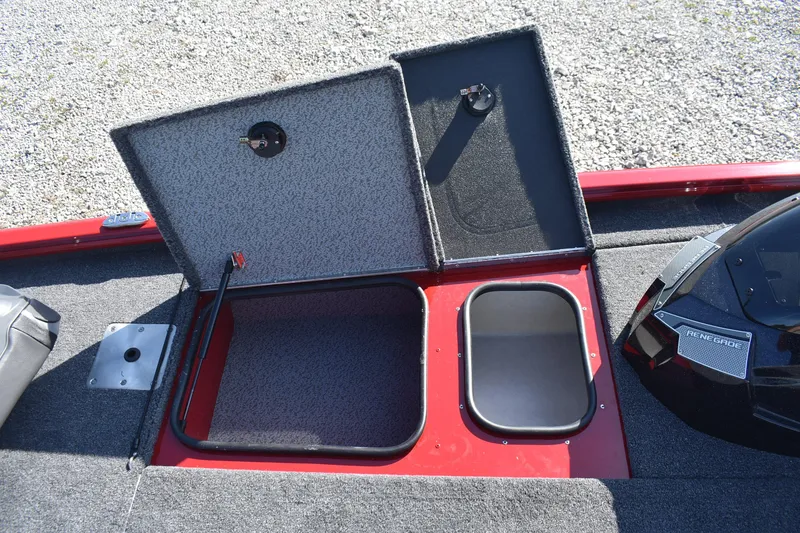 Slide: The Image of 2026 Lund 1875 Renegade boat storage compartments with open lids on a gravel surface. - 13