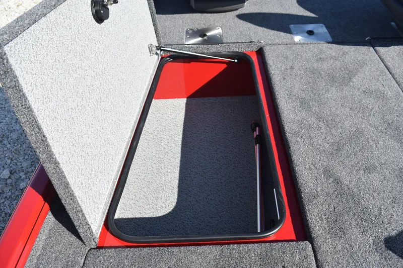 Slide: The Image of Open storage compartment in 2026 Lund 1875 Renegade boat, featuring gray carpet interior. - 14