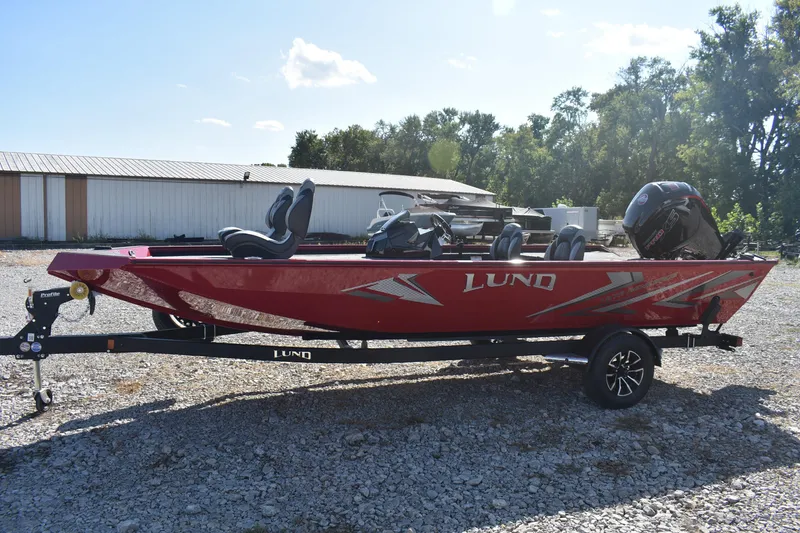 Slide: The Image of 2026 Lund 1875 Renegade boat in red on a trailer, parked outdoors. - 7