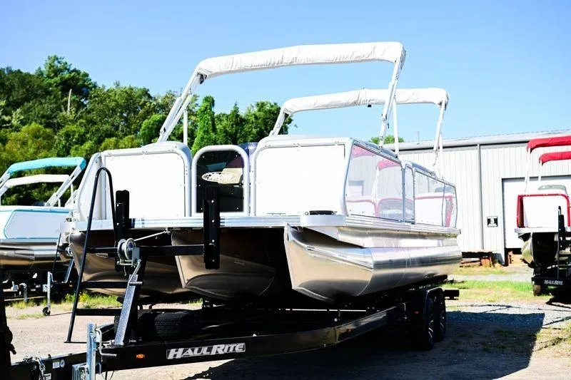 Slide: The Image of 2023 Aloha Pontoon Mahalo 23 on trailer, parked outdoors under clear blue sky. - 2