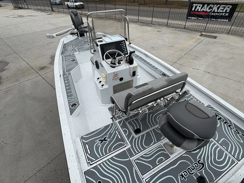 Slide: The Image of 2020 Xpress H20 B boat interior with steering console and seating, parked outdoors. - 13