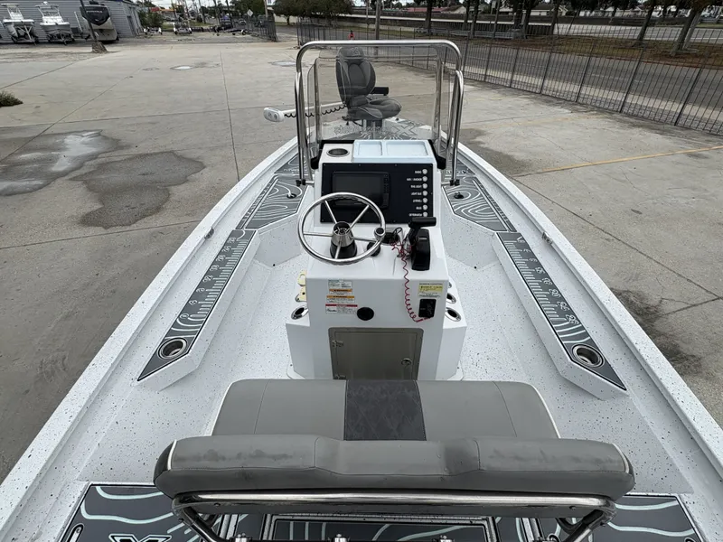 Slide: The Image of 2020 Xpress H20 B boat interior with steering console and seating, parked outdoors. - 5
