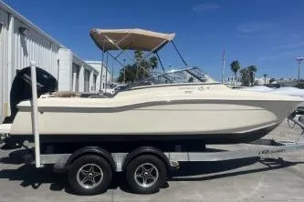 Slide: The Image of 2022 Scout 210 Dorado boat on trailer, parked outdoors under clear blue sky. - 1