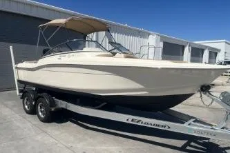 Slide: The Image of 2022 Scout 210 Dorado boat on trailer, parked outdoors near industrial buildings. - 2