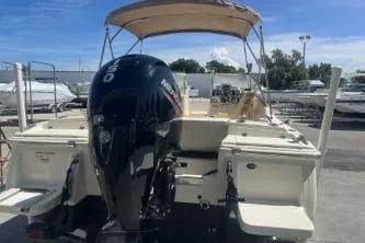 Slide: The Image of 2022 Scout 210 Dorado boat with outboard motor and canopy, parked outdoors. - 5