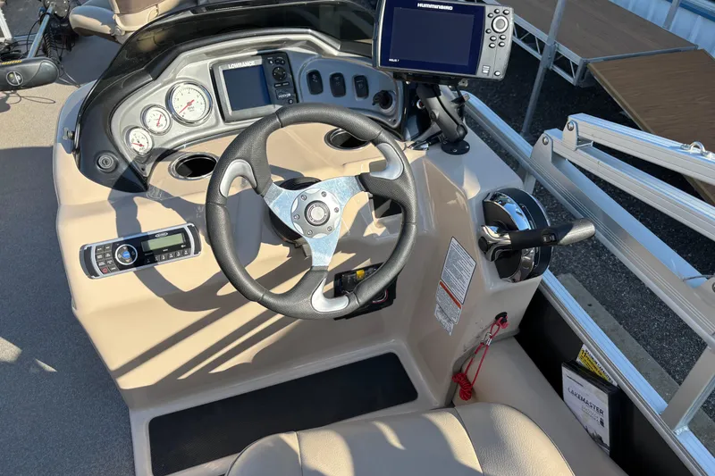 Slide: The Image of 2017 Sun Tracker Fishin' Barge 22 XP3 dashboard with steering wheel and navigation controls. - 16