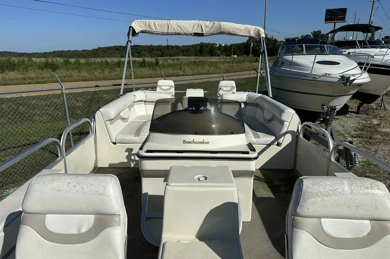Slide: The Image of 2003 Beachcomber 24 Fish & Play boat with white seating and canopy, parked outdoors. - 11