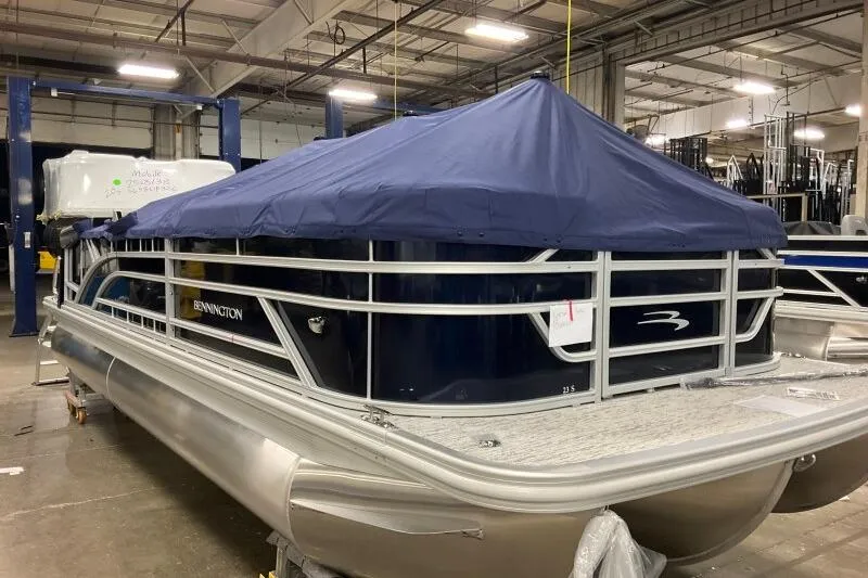 Slide: The Image of 2026 Bennington 23 SSBSF pontoon boat with blue cover in a warehouse setting. - 10