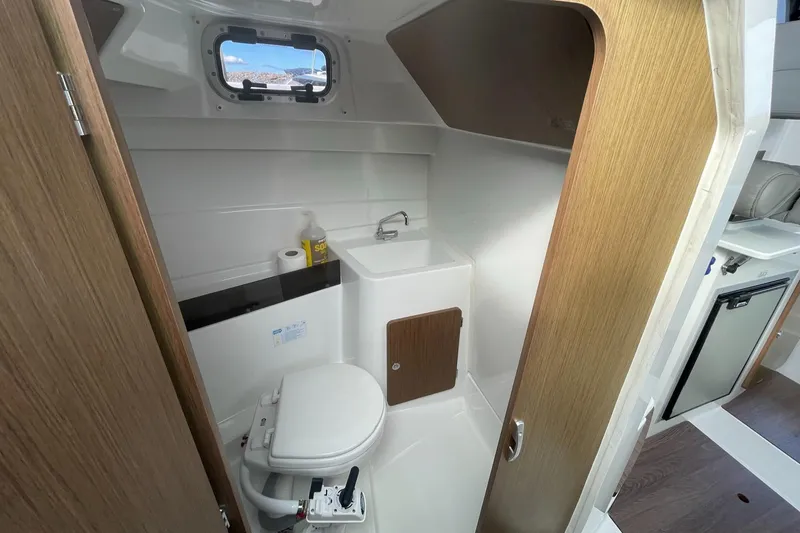 Slide: The Image of 2020 Beneteau Antares 23 boat bathroom with sink, toilet, and wooden accents. - 17