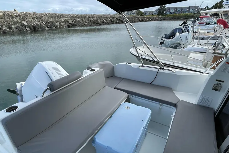 Slide: The Image of 2020 Beneteau Antares 23 boat with cushioned seating and outboard motor, docked in a marina. - 22