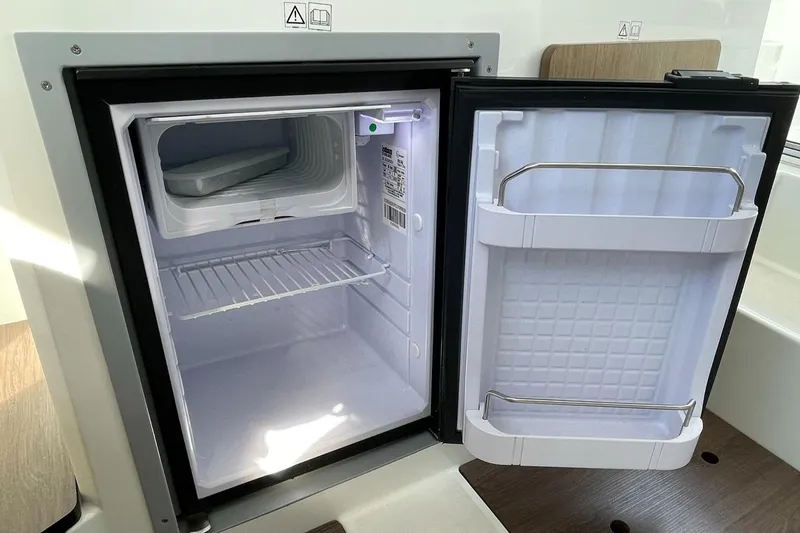 Slide: The Image of Open refrigerator inside 2020 Beneteau Antares 23 boat, showcasing storage space. - 28