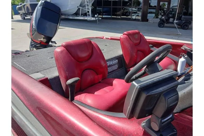 Slide: The Image of 2001 Triton TR19 boat with red seats and steering wheel, parked outdoors. - 11