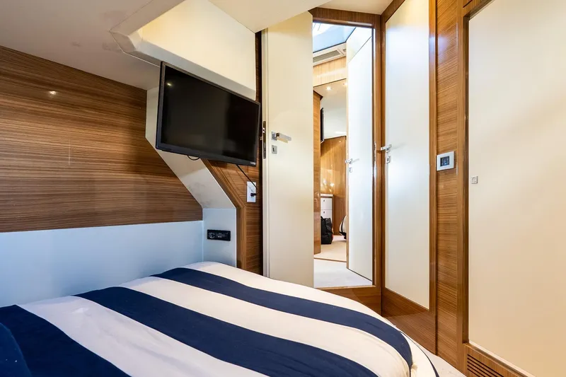Slide: The Image of Luxurious 2011 Uniesse 55S yacht cabin with striped bedding and wall-mounted TV. - 34