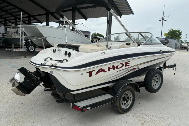 Slide: The Image of 2010 Tahoe Q4 boat on trailer, parked outdoors near other boats. - 7