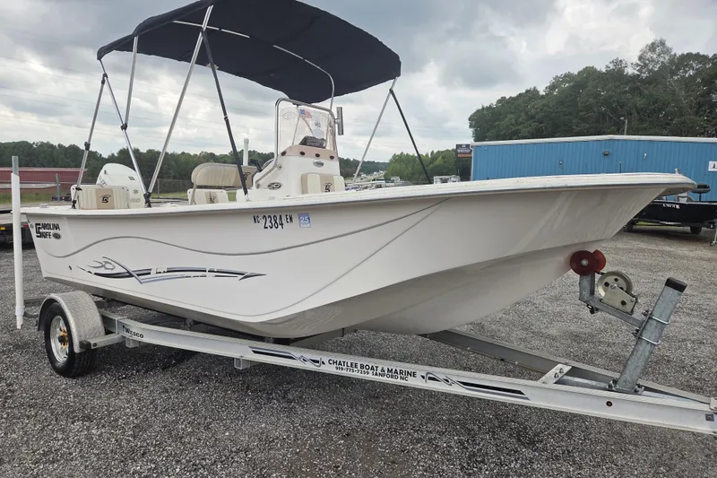 Slide: The Image of 2019 Carolina Skiff 198 DLV boat on trailer with canopy, parked outdoors. - 2