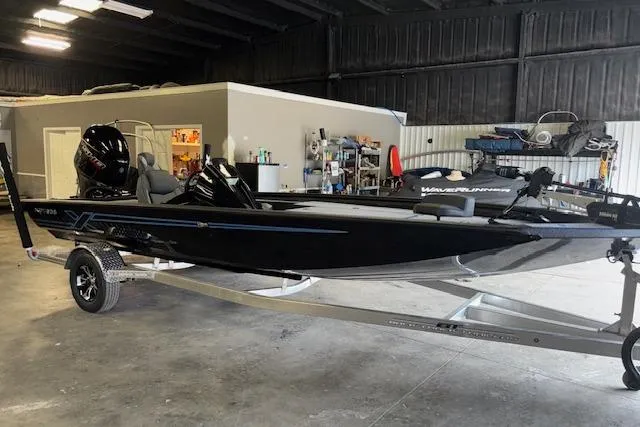 The Image of 2026 Xpress H20 Bass boat in a garage, sleek black design on trailer. - 0