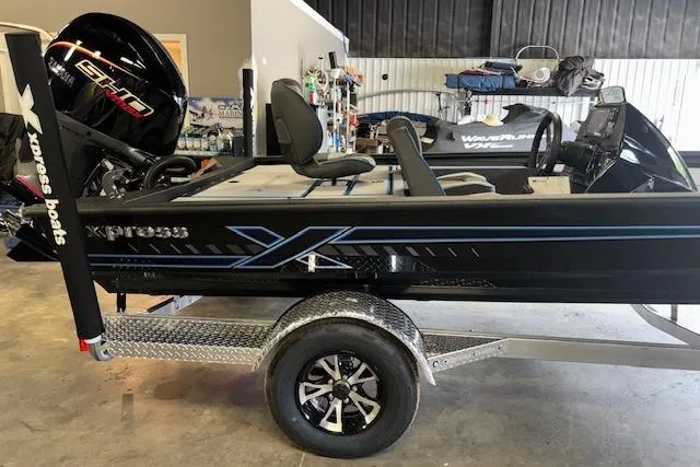 Slide: The Image of 2026 Xpress H20 Bass boat on trailer in garage, featuring sleek black design. - 12