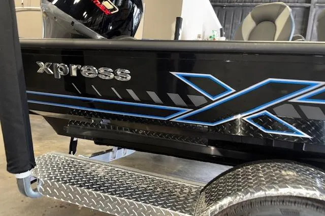 Slide: The Image of 2026 Xpress H20 Bass boat with sleek black and blue design on trailer. - 25