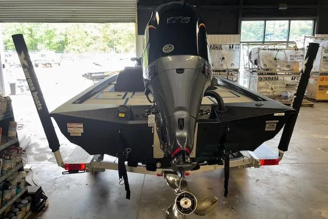 Slide: The Image of 2026 Xpress H20 Bass boat in garage, rear view with motor and trailer. - 28