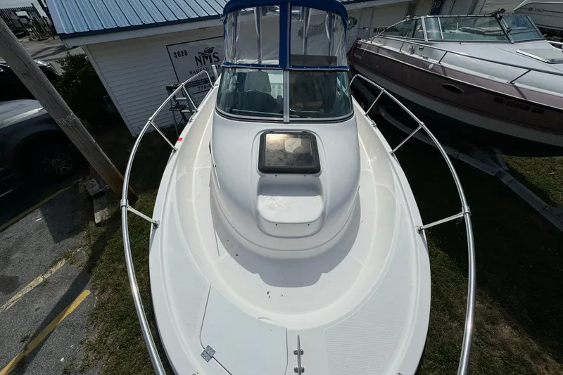 Slide: The Image of 1999 Trophy Bayliner boat with blue canopy, docked beside other vessels. - 4