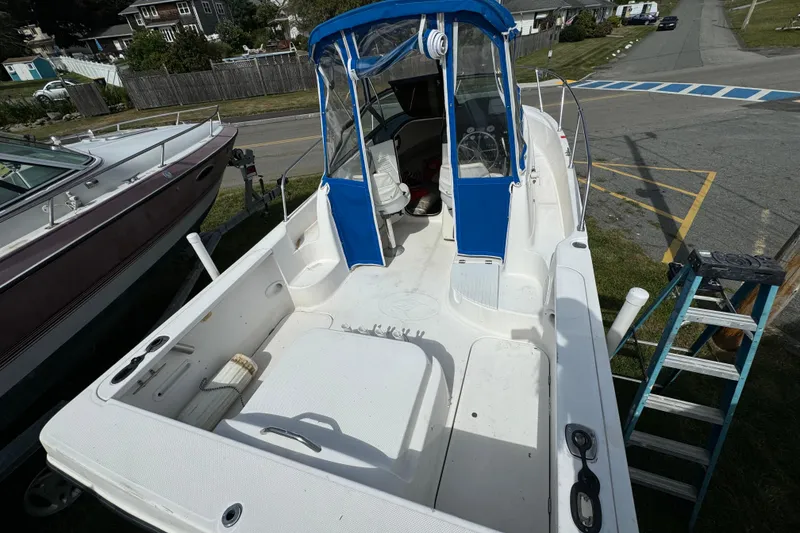 Slide: The Image of 1999 Trophy Bayliner boat with blue canopy, parked on a trailer near a road. - 5