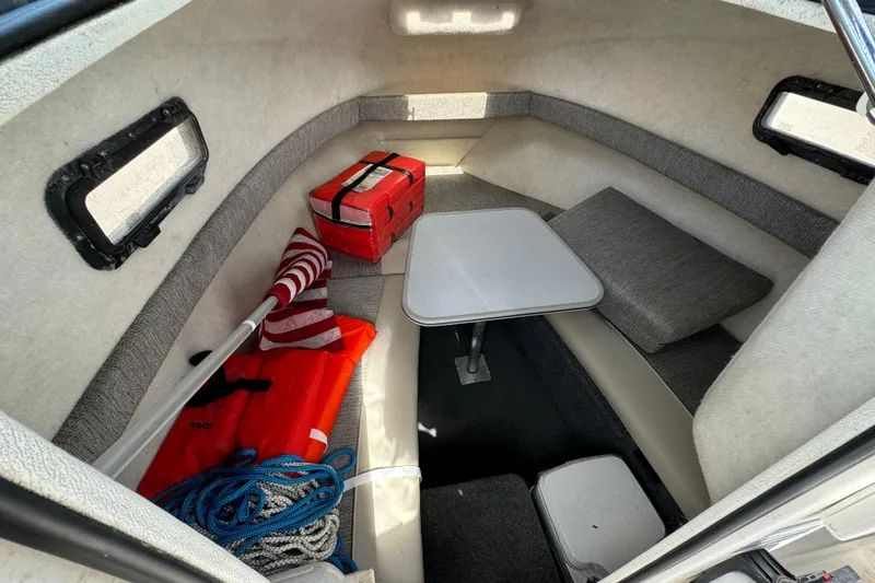 Slide: The Image of 1999 Trophy Bayliner boat interior with table, cushions, life jacket, and storage items. - 7