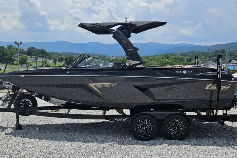 Slide: The Image of 2025 Tigé 22RZX boat on trailer, sleek black design, mountainous backdrop. - 7
