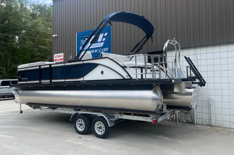 Slide: The Image of 2026 Godfrey SWEETWATER 2286 SFL pontoon boat on trailer, parked outdoors. - 2