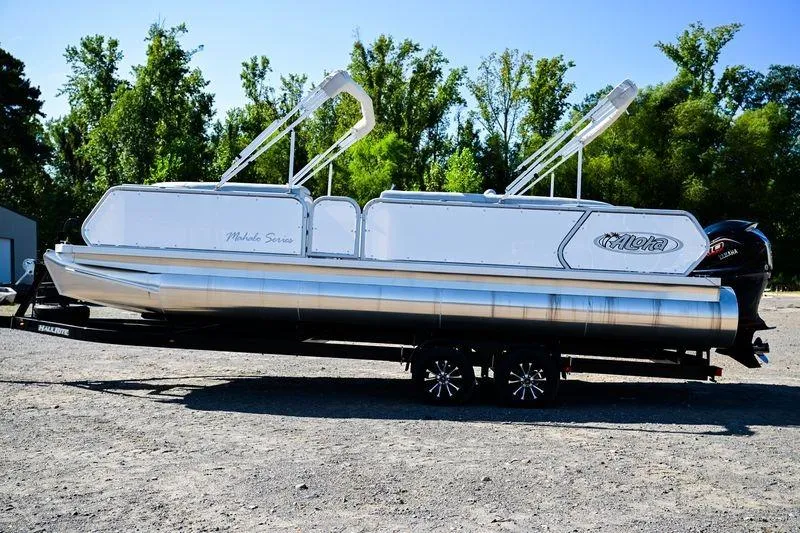Slide: The Image of 2023 Aloha Pontoon Mahalo 23 on trailer, surrounded by trees. - 1