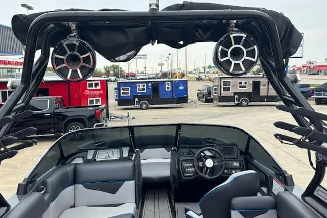 Slide: The Image of 2022 Moomba Kaiyen boat interior with speakers, parked near colorful trailers. - 12