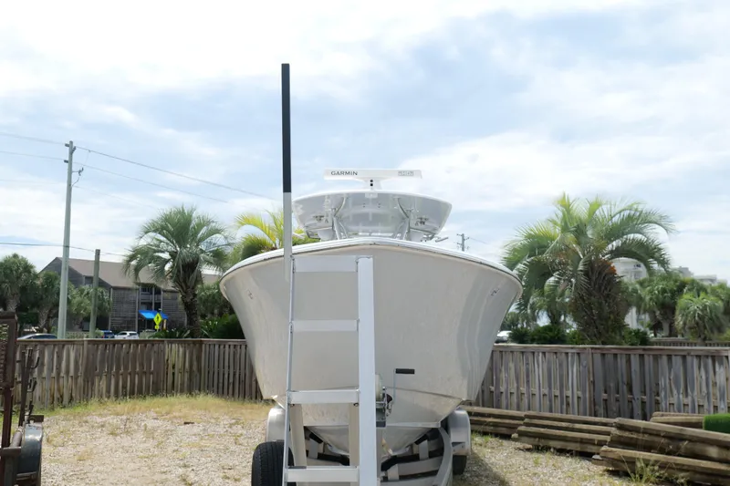 Slide: The Image of 2024 Contender 35 ST boat on trailer, surrounded by palm trees and a wooden fence. - 2