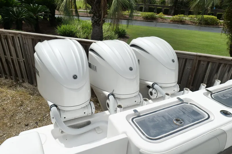 Slide: The Image of Triple Yamaha outboard engines on 2024 Contender 35 ST boat, docked near lush greenery. - 6