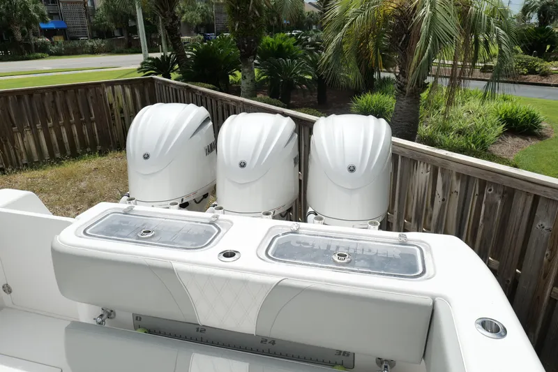 Slide: The Image of 2024 Contender 35 ST boat with triple Yamaha outboard engines, docked near palm trees. - 7