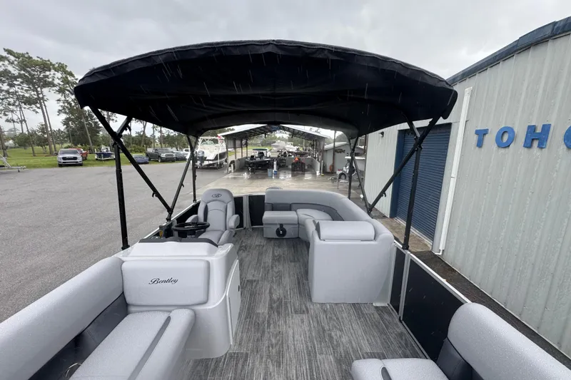 Slide: The Image of 2026 Bentley Pontoons LE 180 Cruise with canopy, parked near a building. - 20