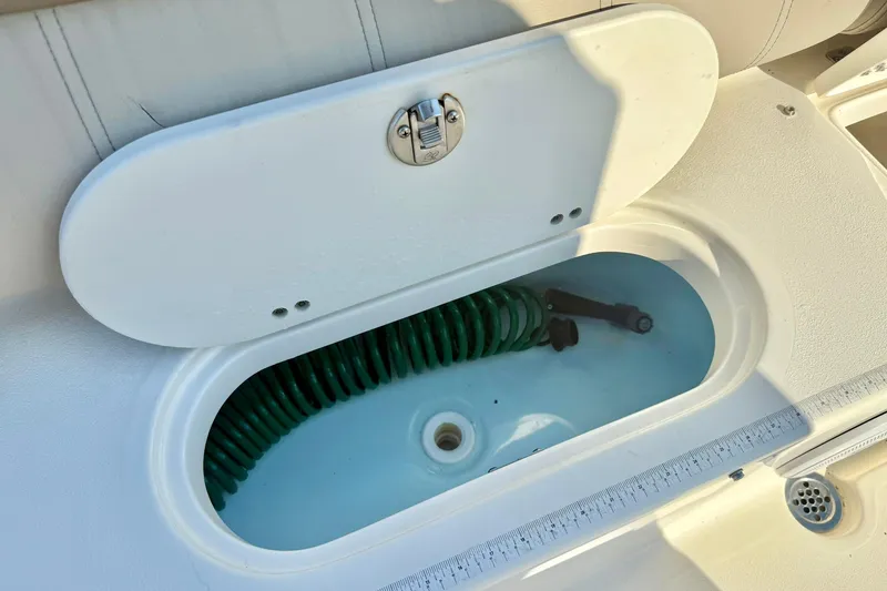 Slide: The Image of 2022 Key West 219 FS boat storage compartment with coiled hose inside. - 41
