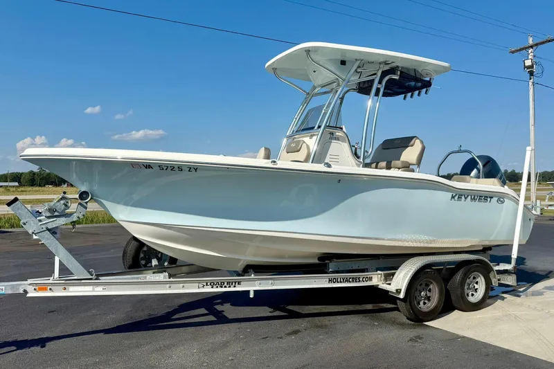 Slide: The Image of 2022 Key West 219 FS boat on trailer, parked outdoors under clear blue sky. - 5