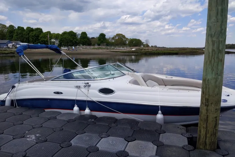 The Image of 2002 Sea Ray 240 Sundeck boat docked on calm water under a cloudy sky. - 0