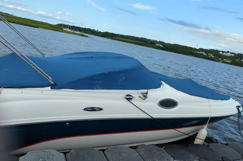 Slide: The Image of 2002 Sea Ray 240 Sundeck boat docked on a calm river with blue cover. - 4