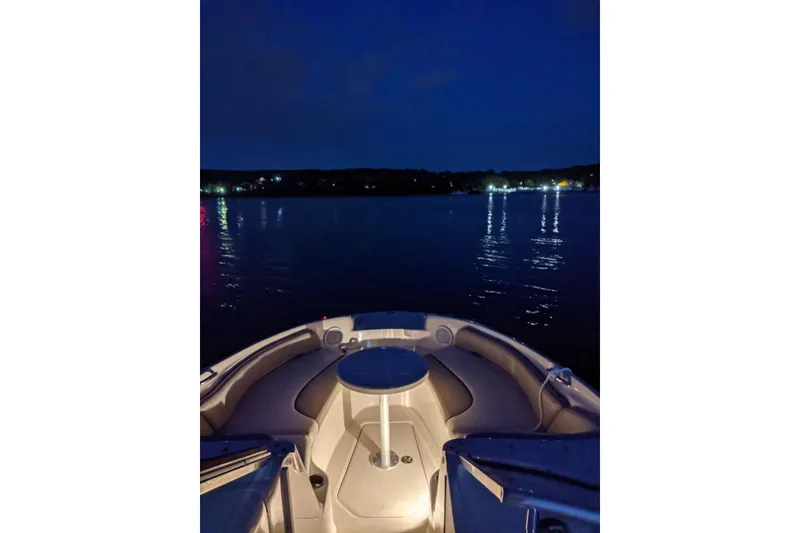 Slide: The Image of 2002 Sea Ray 240 Sundeck boat at night, illuminated interior, calm water reflections. - 5