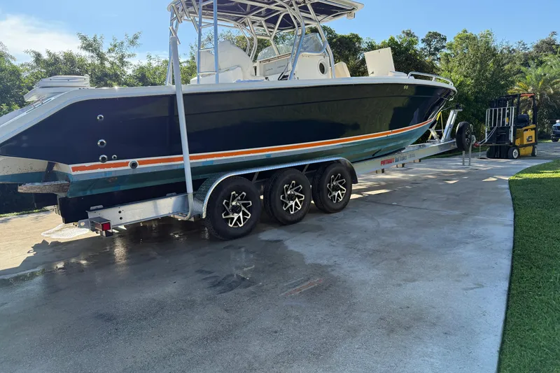 The Image of 2001 Marlago 35 Cuddy boat on trailer, parked on driveway, surrounded by greenery. - 0